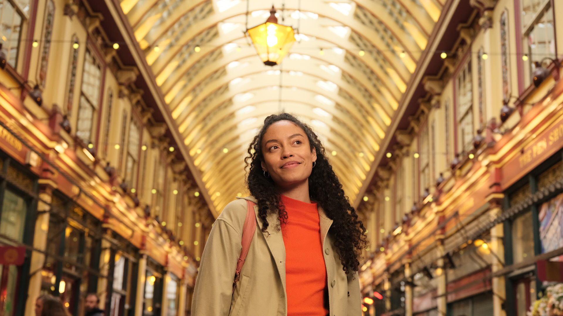 8 best Instagrammable places in London - Leadenhall Market - woman smiling and looking across the market, rows of shops in background