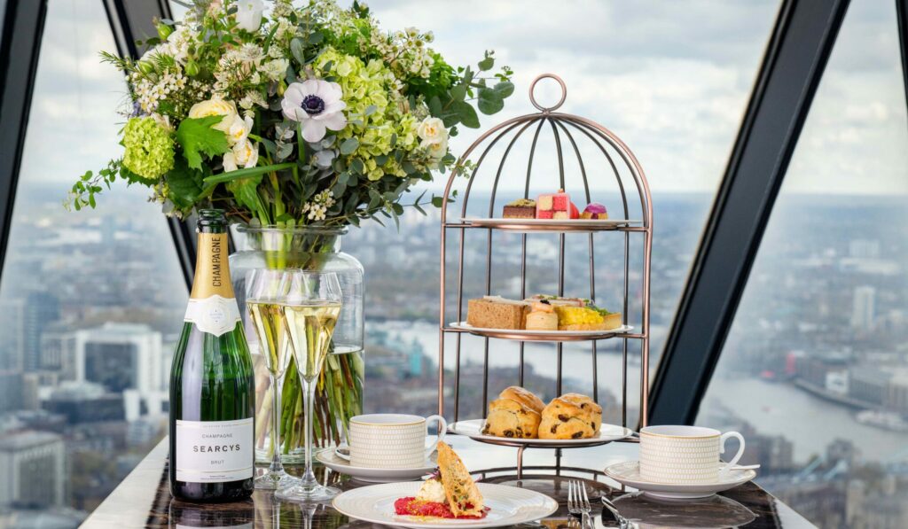 Afternoon Tea Spots in the City of London - Searcys Gherkin afternoon tea - spread of fizzy wine and pastries on a cake stand with a bunch of flowers