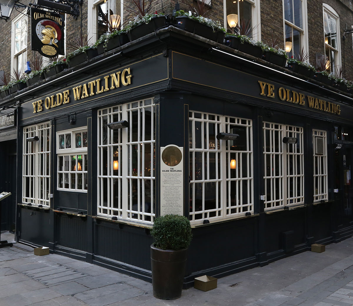 9 Best Pubs in the City of London - Ye Olde Watling pub exterior on the corner of the street, its a dark black building with gold writing and white window frames.