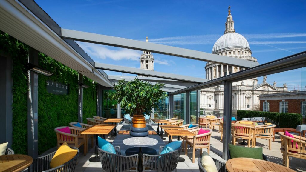 Outdoor rooftop bar(Sabine) - tables and chairs set out on the terrace with a stunning view of St Paul's Cathedral in the background.