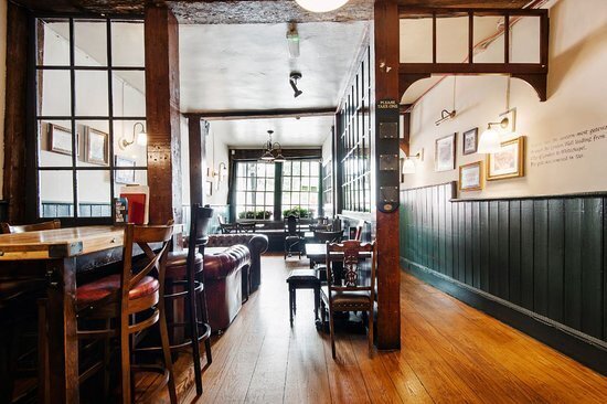 9 Best Pubs in the City of London - The Hoops and grapes pub interior, with wooden floors and in an old building with wooden beams  going across the ceiling