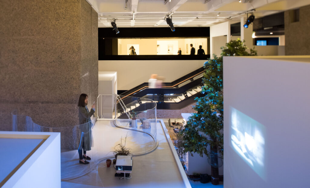 Art in the City of London - Barbican Art Gallery - woman looking at a film on a screen with the gallery space behind