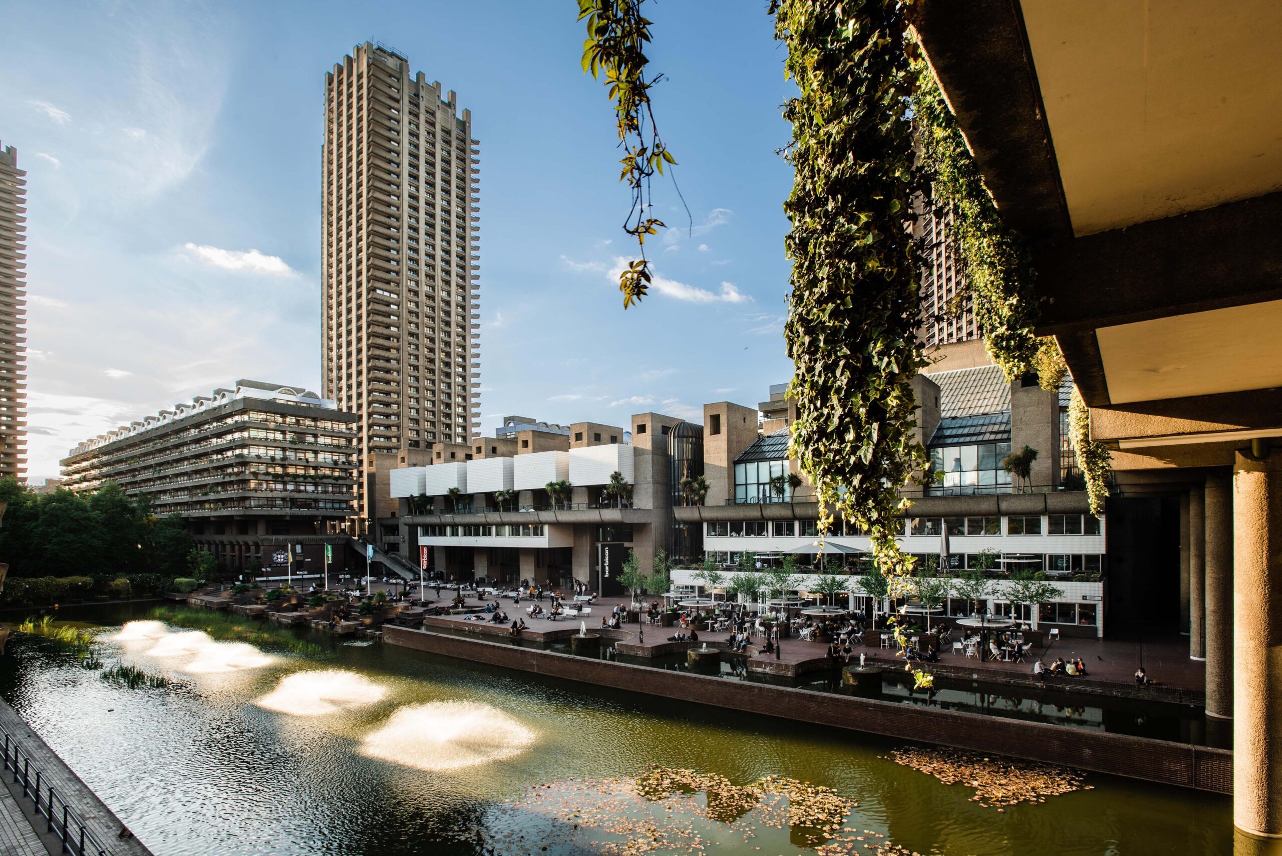 8 best Instagrammable places in London - The Barbican Centre - view across the lake and terrace to the Barbican centre building, tall block of high rise brutalist flat in the background