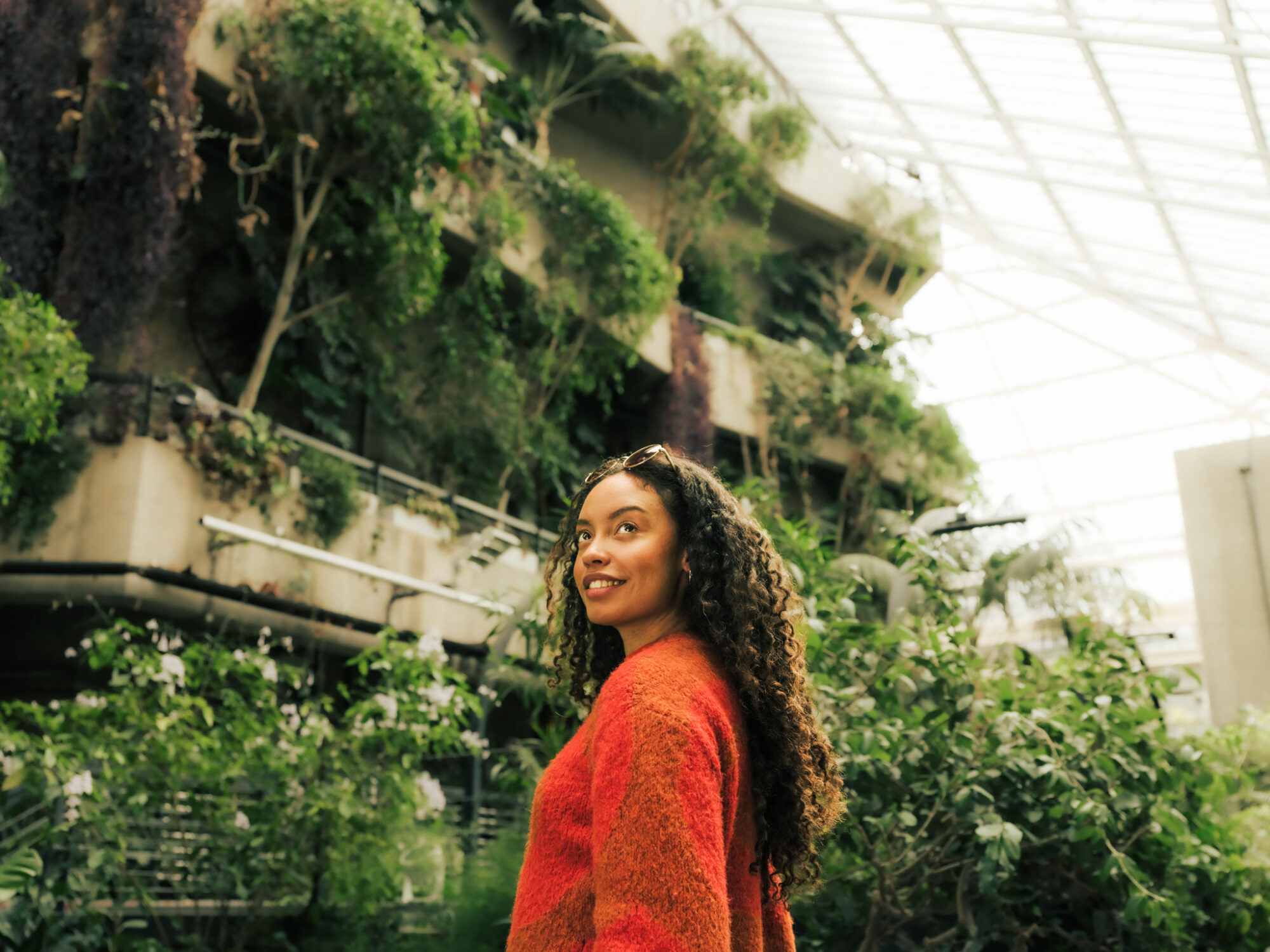 Yoga, Spas and Green Spaces in the City of London - woman in the Barbican Conservatory - tropical plants in background growing over concrete balconies