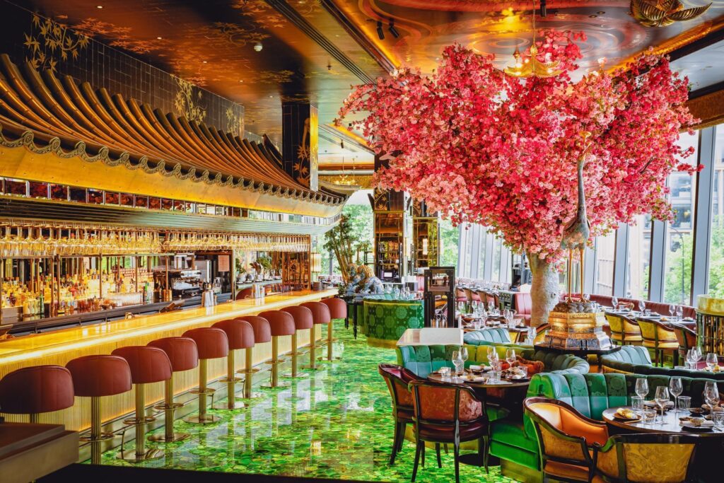 19 best restaurants to eat in the City of London - The Ivy Asia St Paul's - vibrant restaurant interior, asian style curved roof over bar, large red blossom covered tree among dinning tables