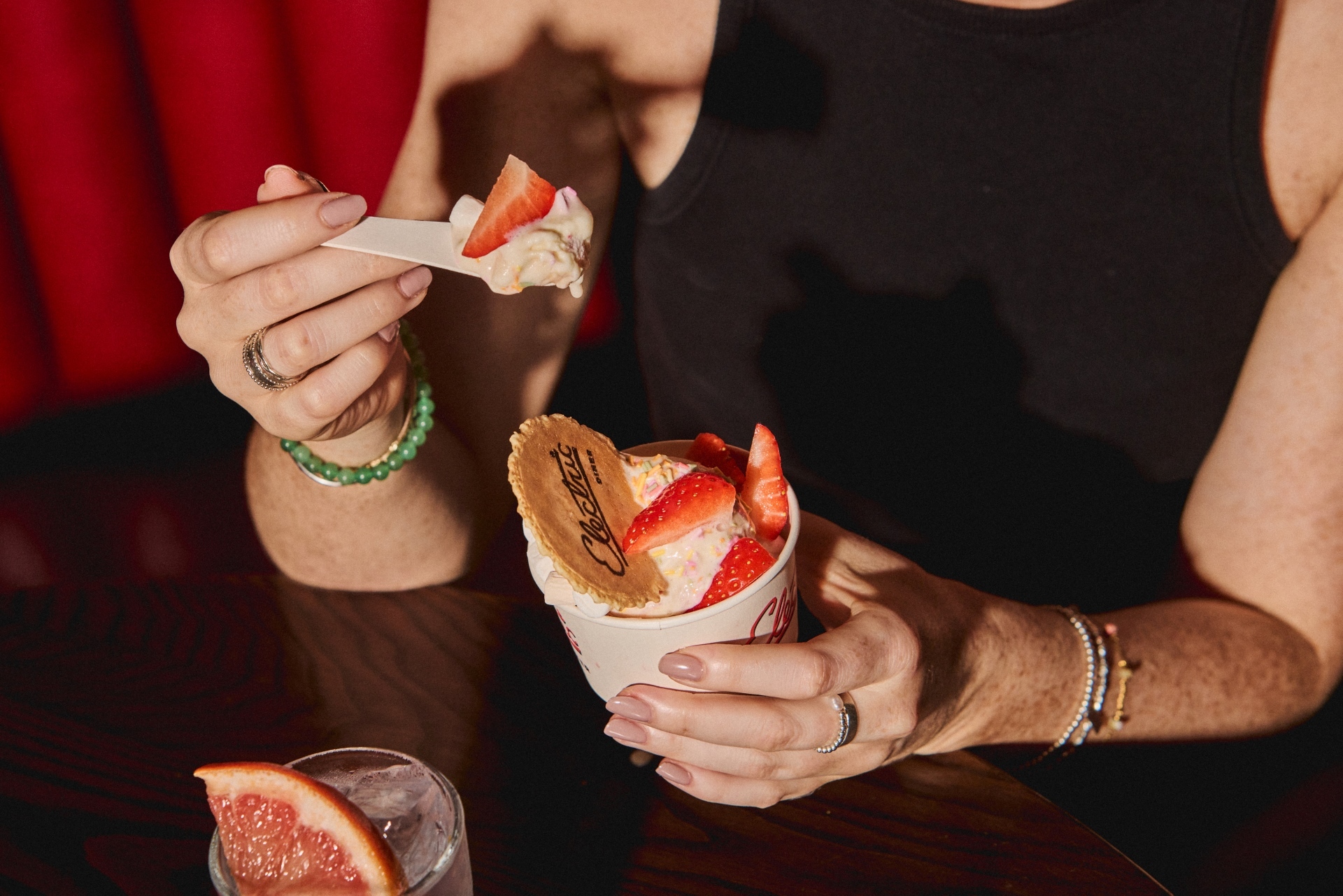 Person holding an individual portion of ice cream and strawberries in a tub.
