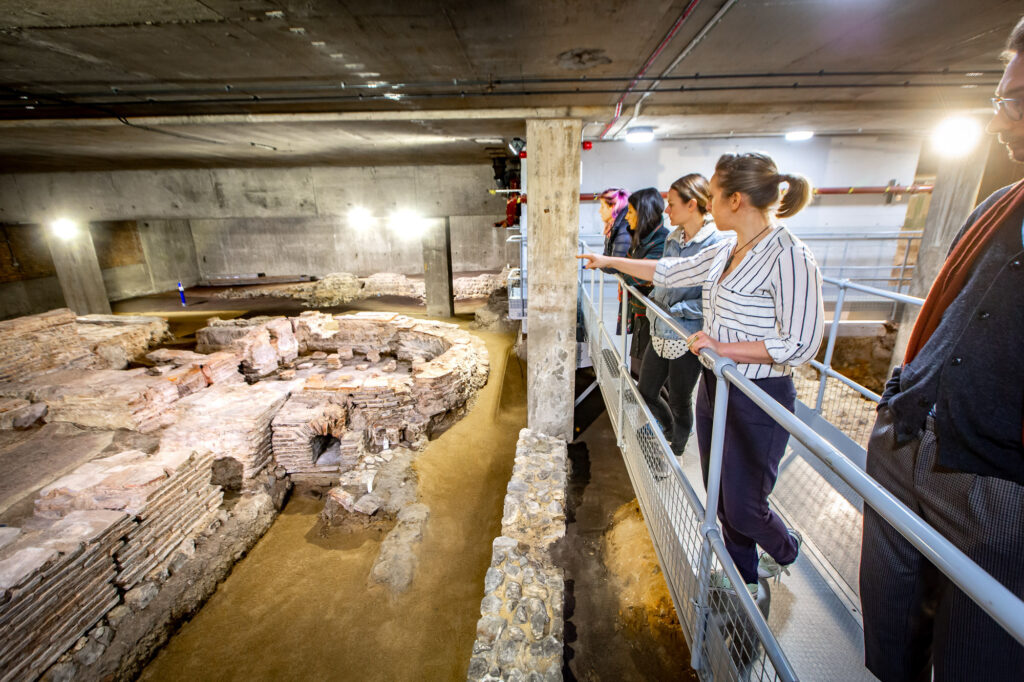 Roman ruins in the City of London - Billingsgate Roman Bath House - tour group looking down at roman ruins from viewing platform