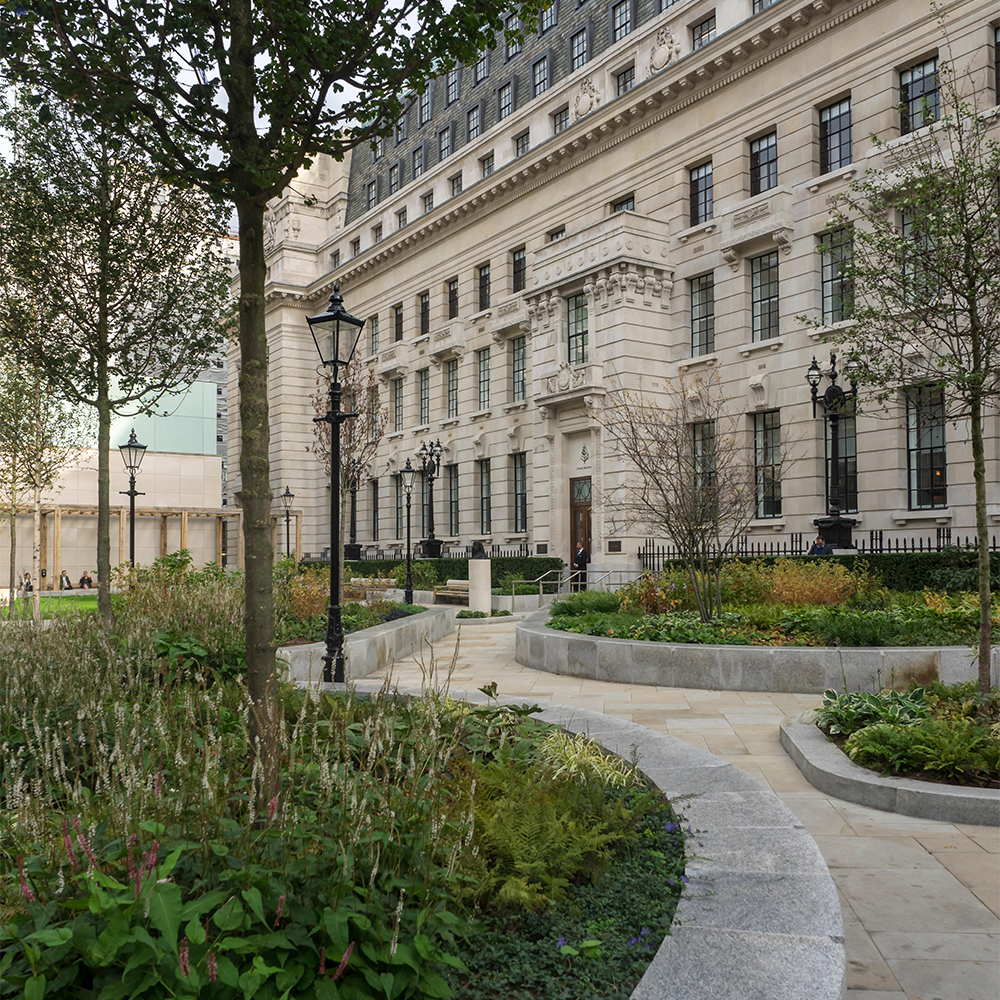 Image of a park with raised flower beds and a building at the end of the path