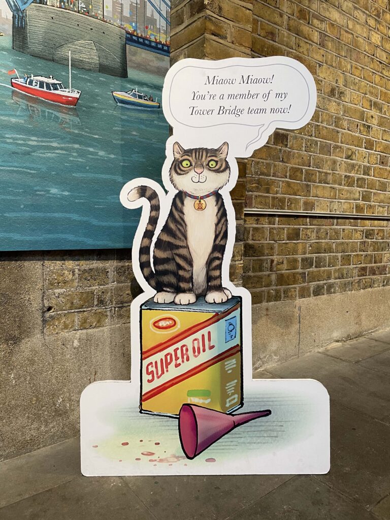 The Tower Bridge Cat Trail - card cut out of a cartoon cat sat on an oil bottle