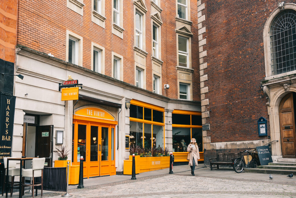 The Vintry - bright orange bar exterior - on the street adjacent to a brick church