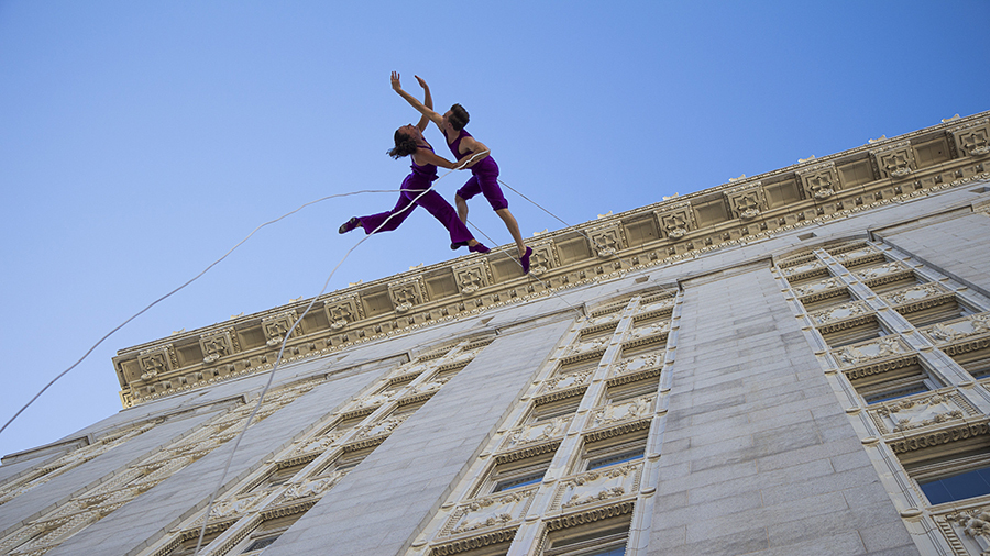 Dancers performing aerial dance on a stone building facade