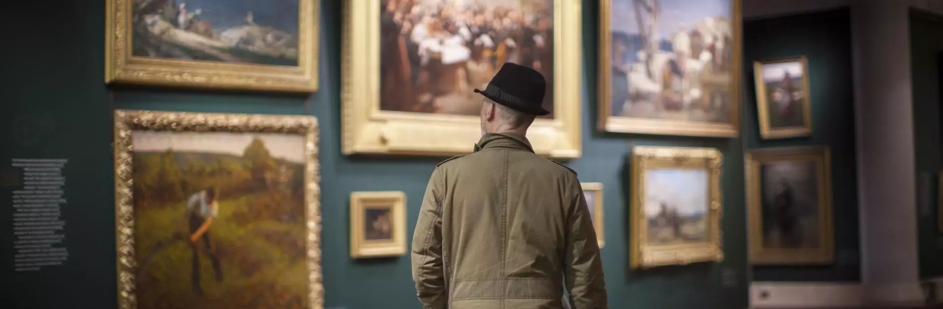 Guildhall Art Gallery - man in a hat looks at paintings on the wall