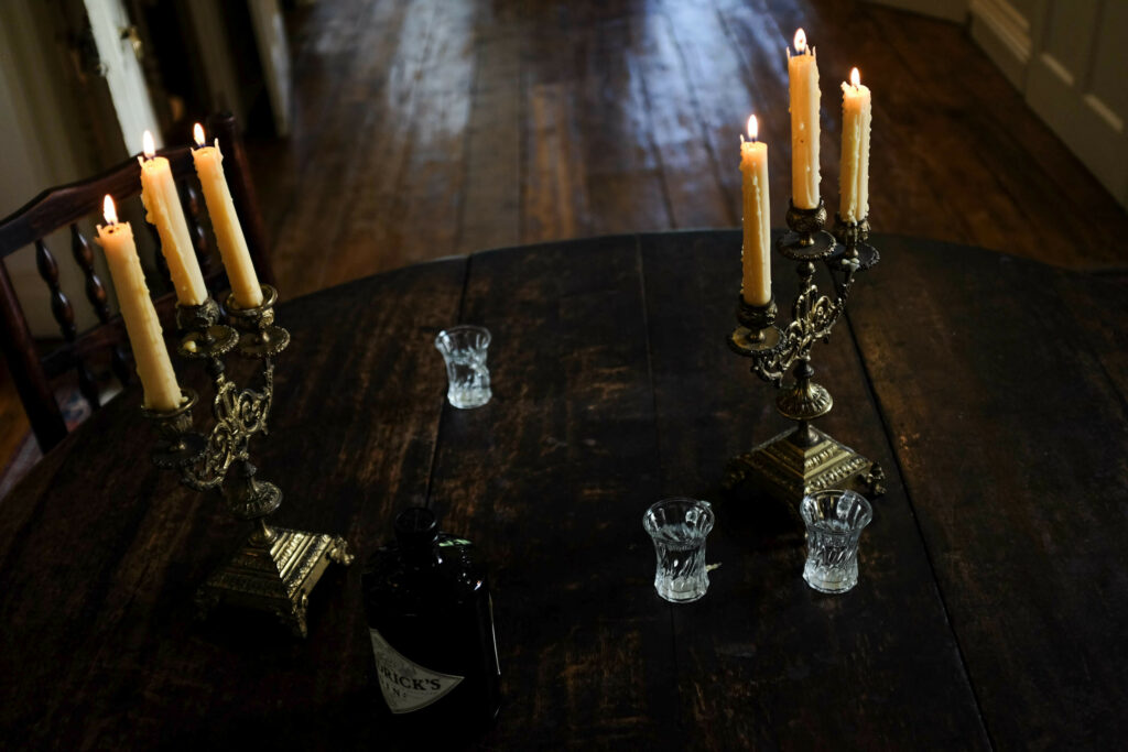 An elegant setting with lit candles in silver candelabras and several glass holders on a dark wooden table.