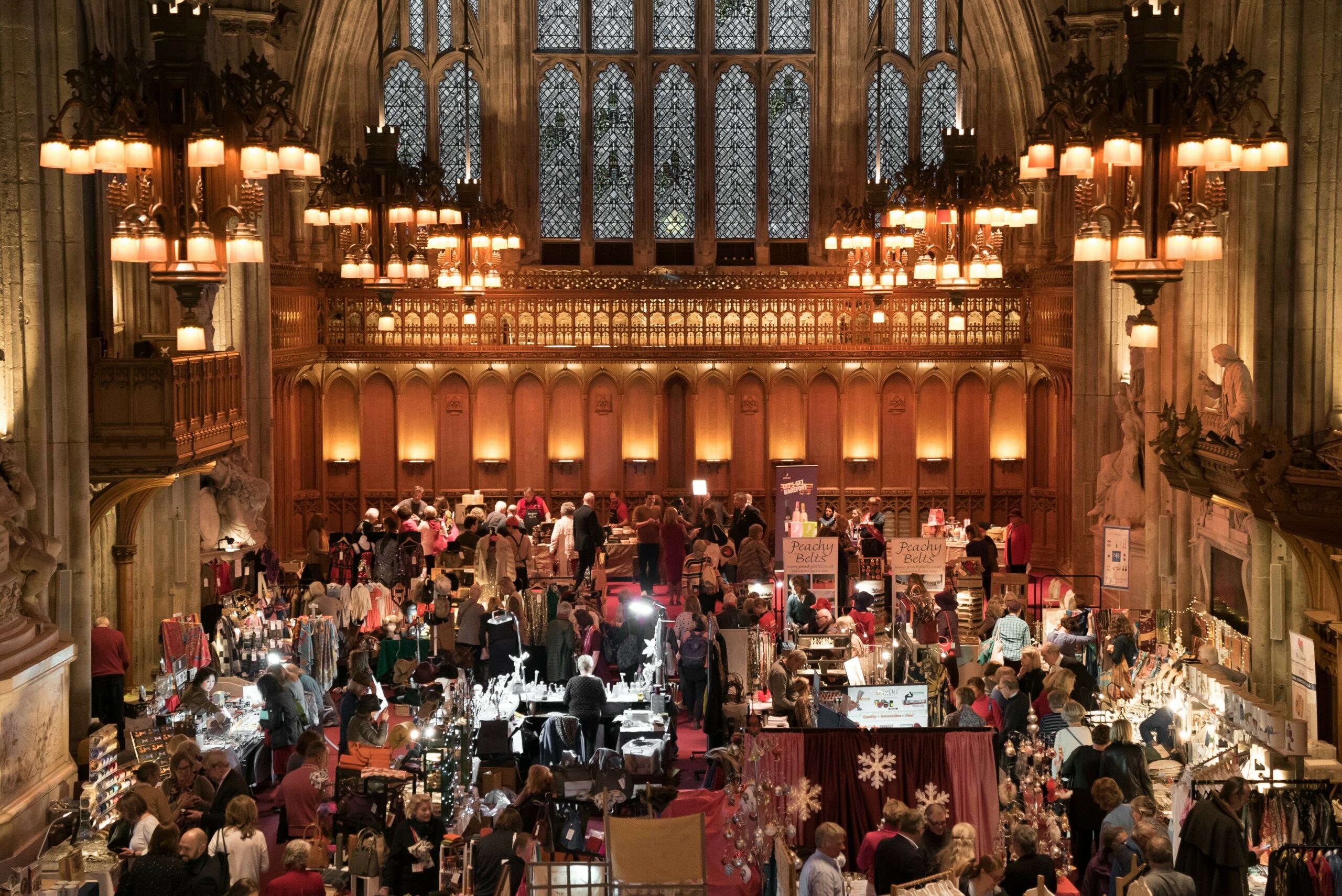People walking through a Christmas market inside a medieval hall