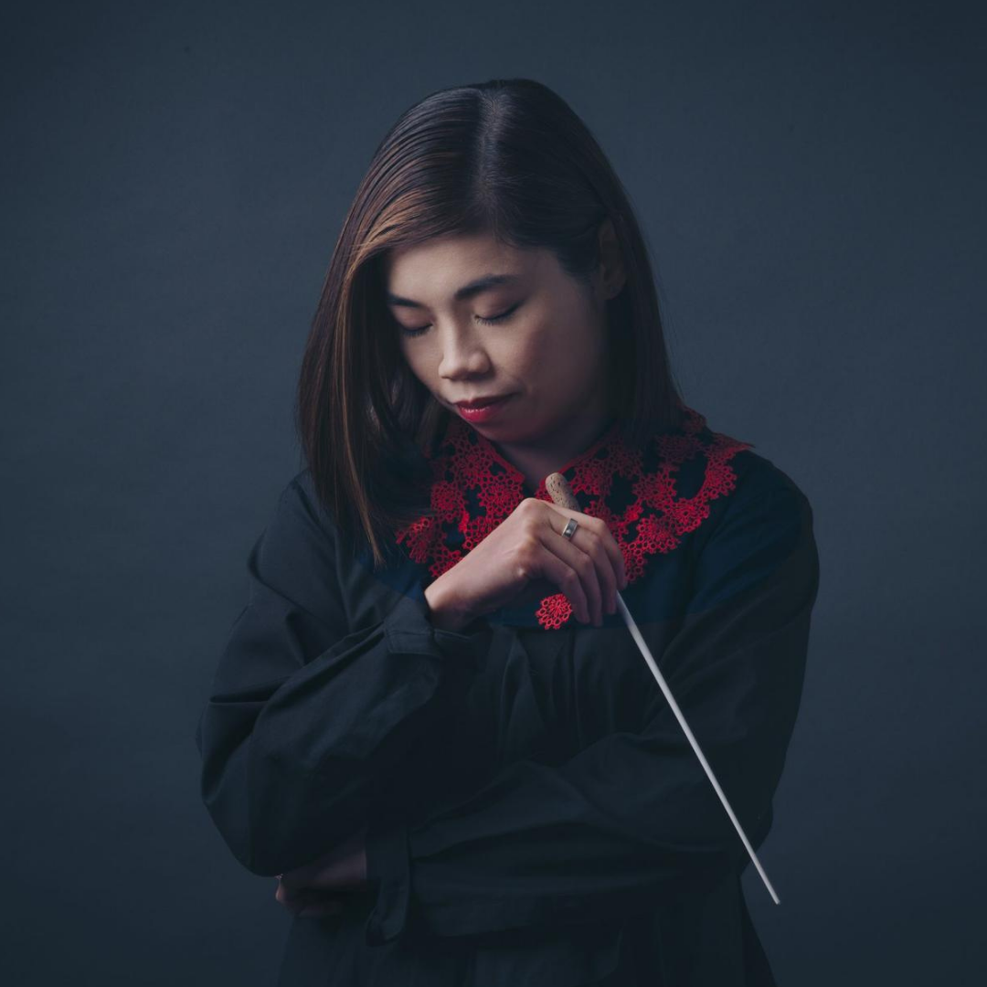 A portrait photo of conductor Elim Chan on a dark background