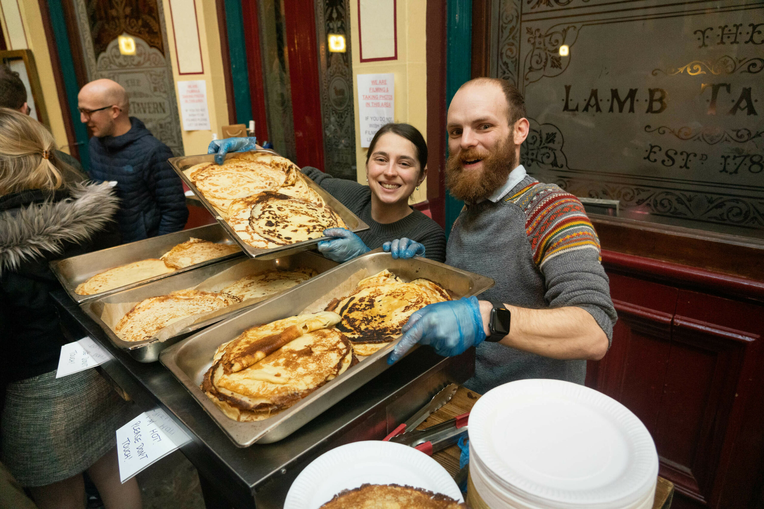 man and woman holding trays of pancakes