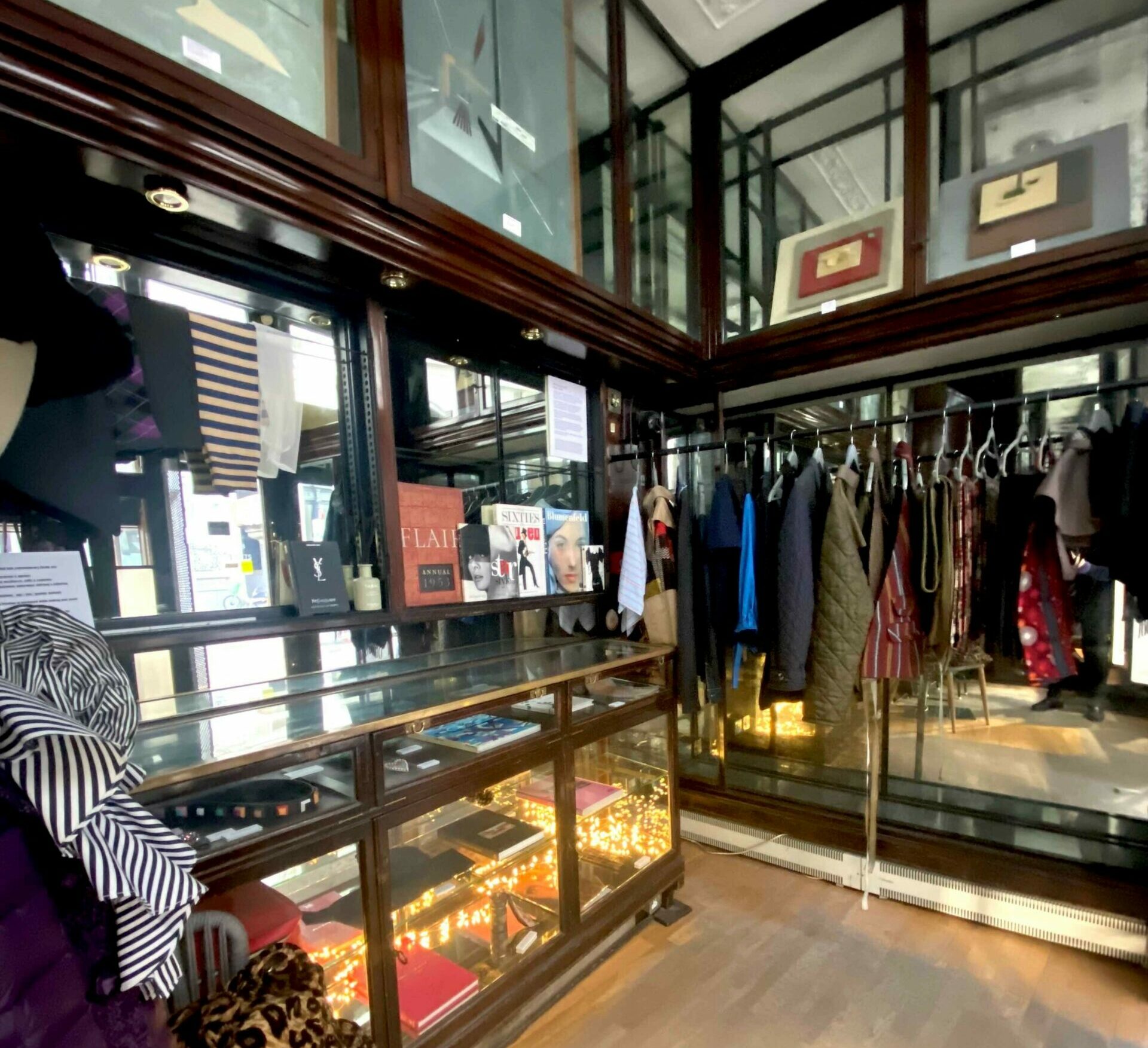 Interior of a shop with a glass counter and clothing, books and other items on display