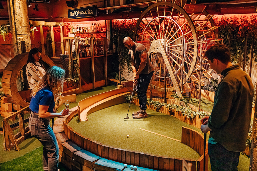 Group of four friends playing at the waterwheel at a mini golf venue