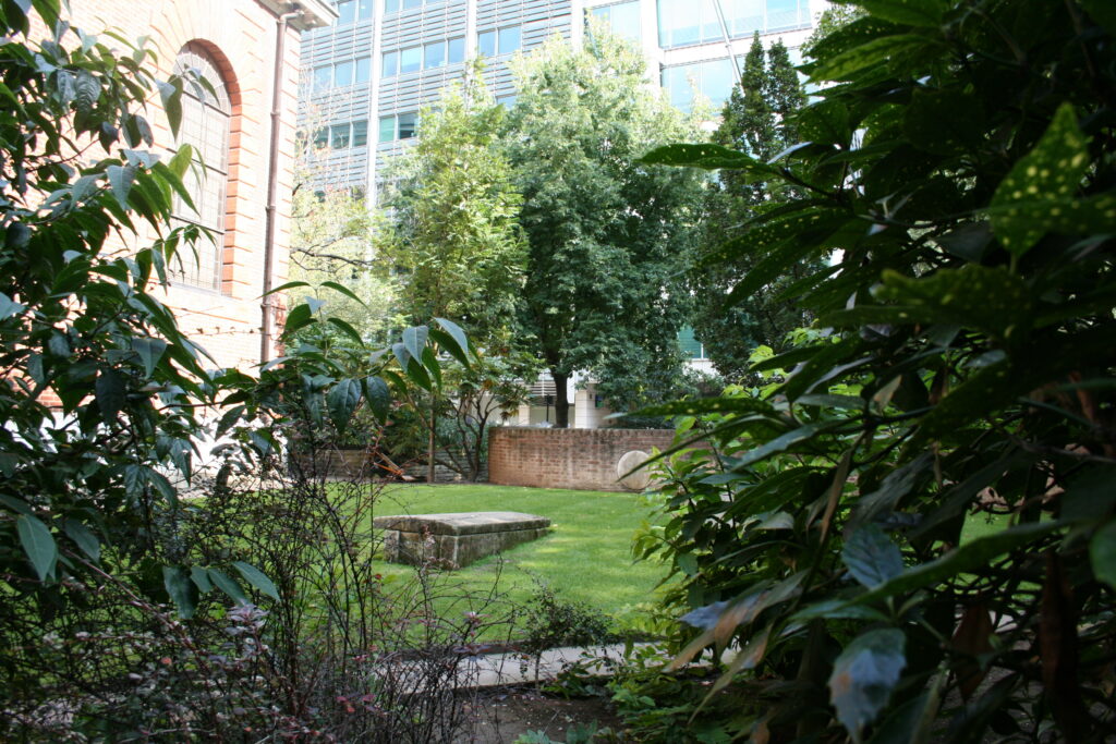 St Olave, Hart Street Churchyard with a green lawn and trees.