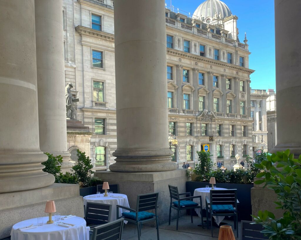 Outside terrace of the Royal Exchange with four tables covered in white table cloths.
