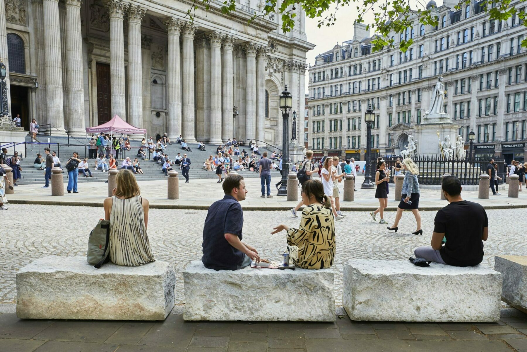 People sat atop large stones which now serve as benches infront of St Pauls