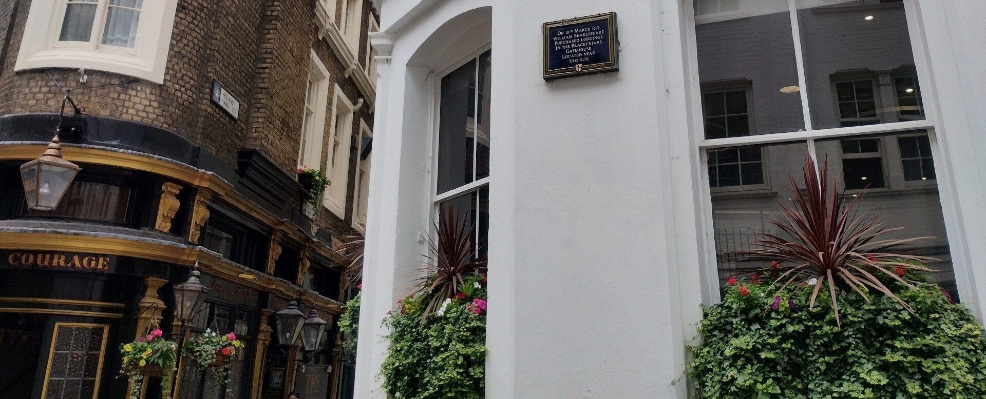 City of London Blue Plaque on a white building, opposite a historic pub.