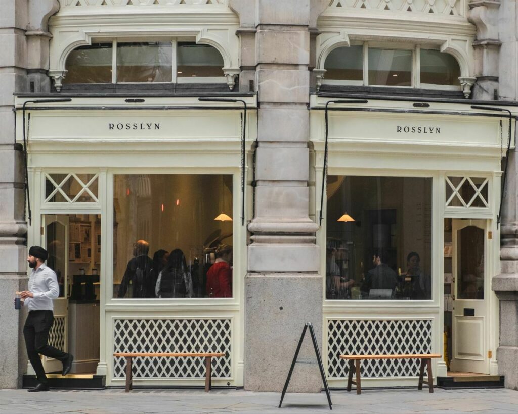 Rosslyn, a coffee shop located in the City of London, with a cream facade that stands out against the stone structure of the Royal Exchange.