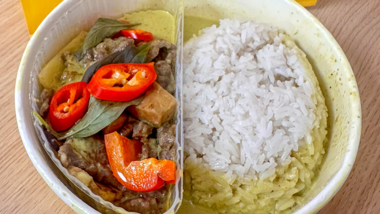 Round bowl half filled with white rice and another with a green curry with beef