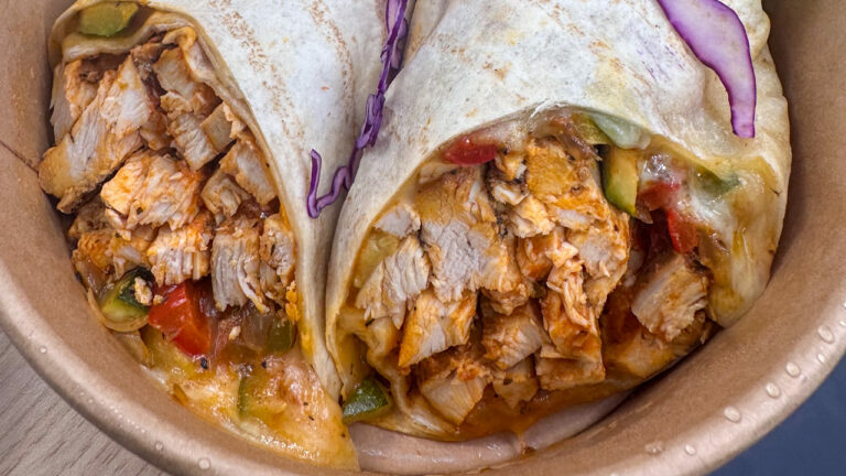 Close up of the open end of two wraps filled with chicken, veg and cheese