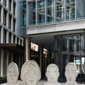 Four scupltures in the shape of heads amd faces looking towards the camera